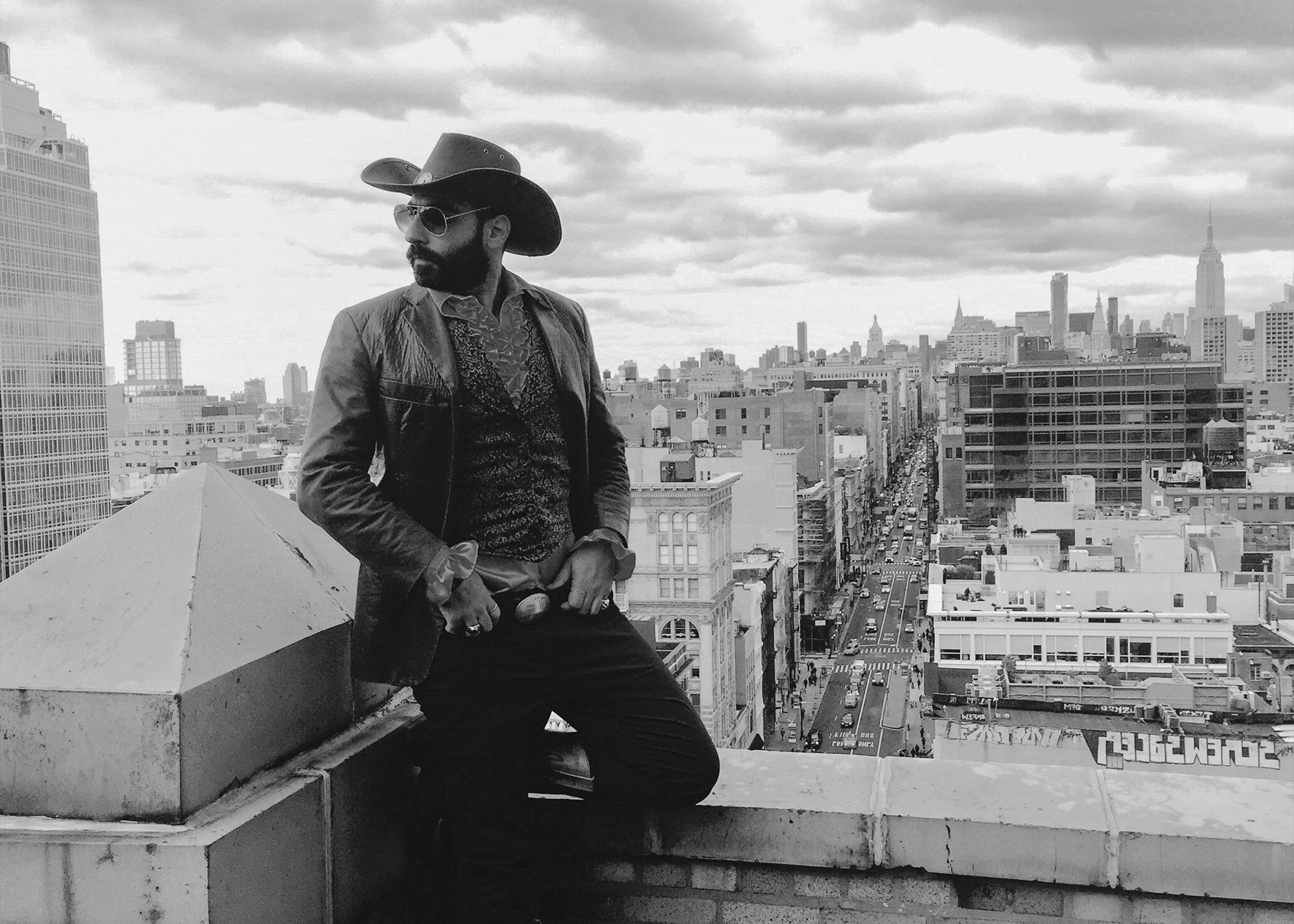 Yohay Sponder in a wide-brimmed hat on a Manhattan rooftop, the New York skyline behind him